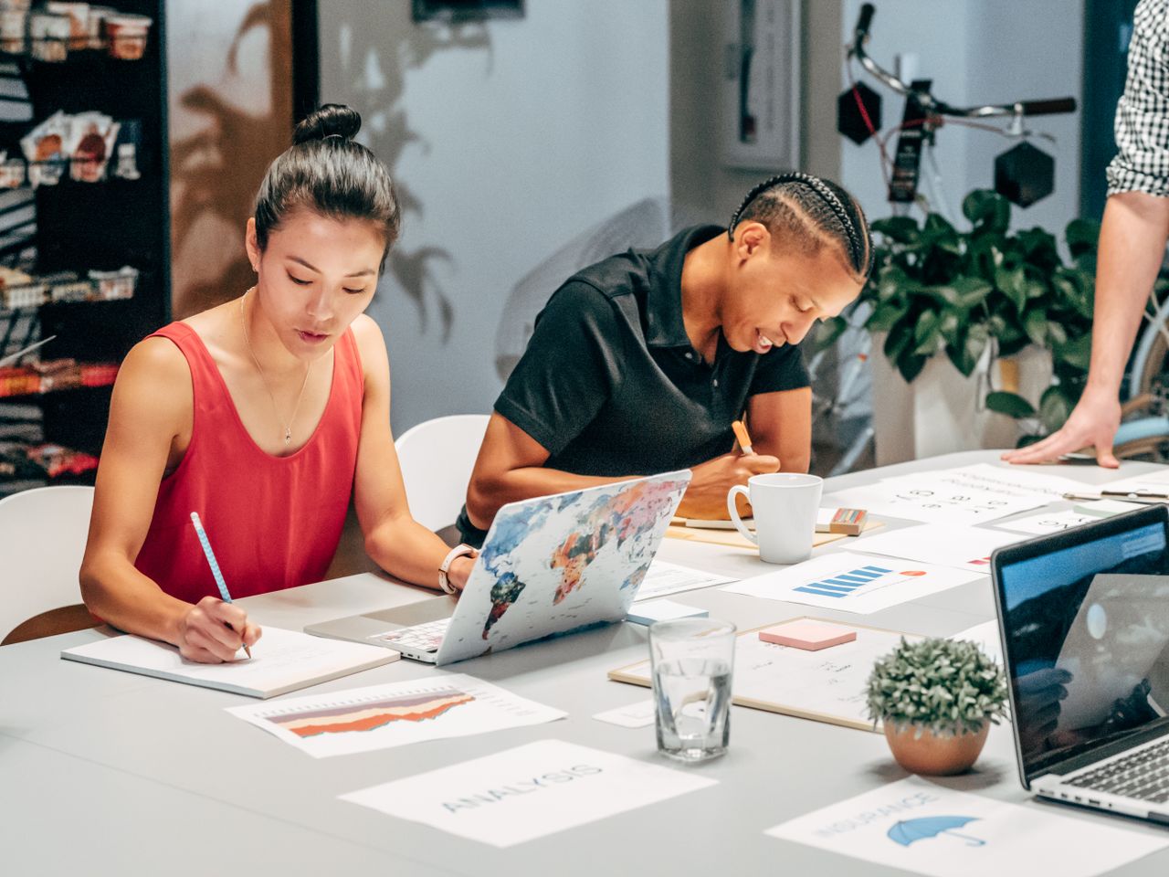 who-we-are A diverse team engaged in a collaborative office meeting, analyzing data and taking notes.