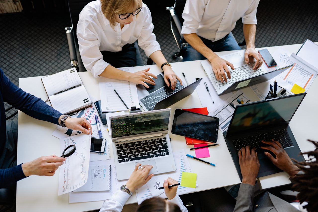 journey Overhead view of a corporate team collaborating with laptops and documents.